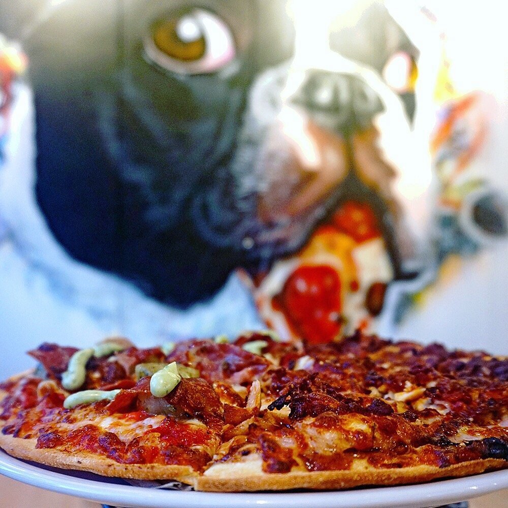 Pizza with iconic dog mural in background